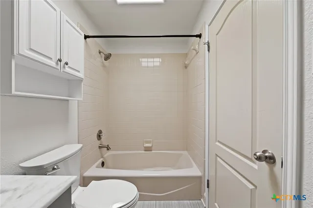 a bathroom with a granite countertop bathtub shower sink vanity and toilet