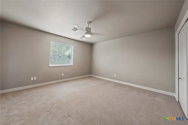 an empty room with a fan & a window