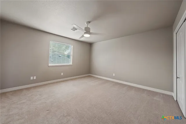 an empty room with a fan & a window