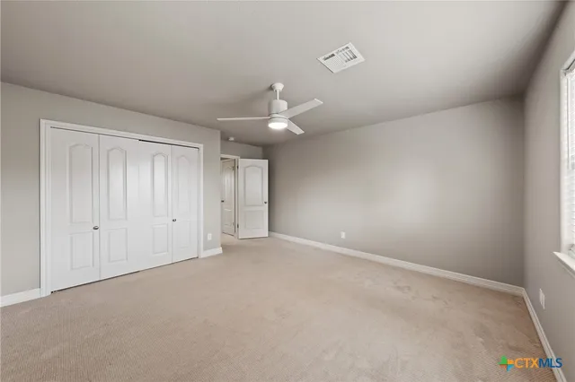 an empty room with a ceiling fan and window