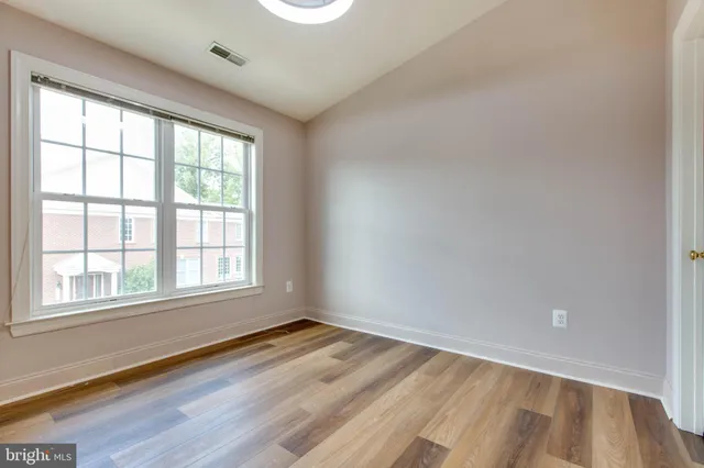a view of an empty room with wooden floor and closet
