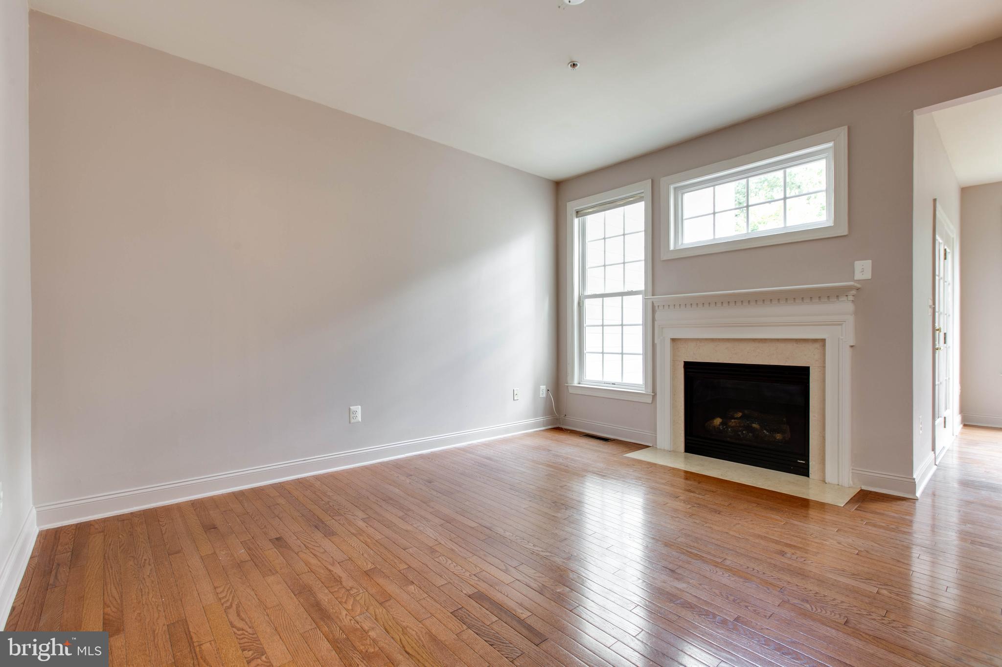 2119 Split Creek Lane Hanover, MD 21076 - Photo 10 of 55 an empty room with wooden floor fireplace and windows