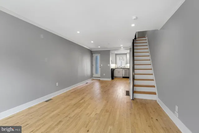a view of empty room with wooden floor and stairs