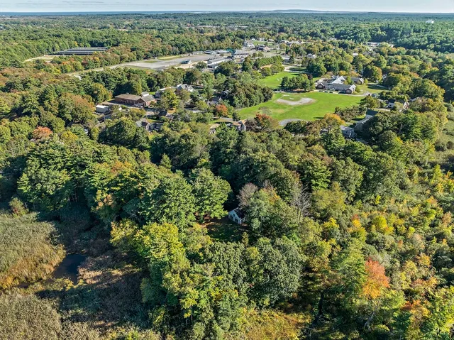 an aerial view of residential houses with outdoor space and trees