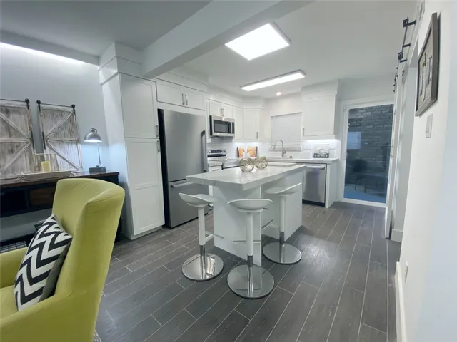 a kitchen with stainless steel appliances wooden floor and dining table