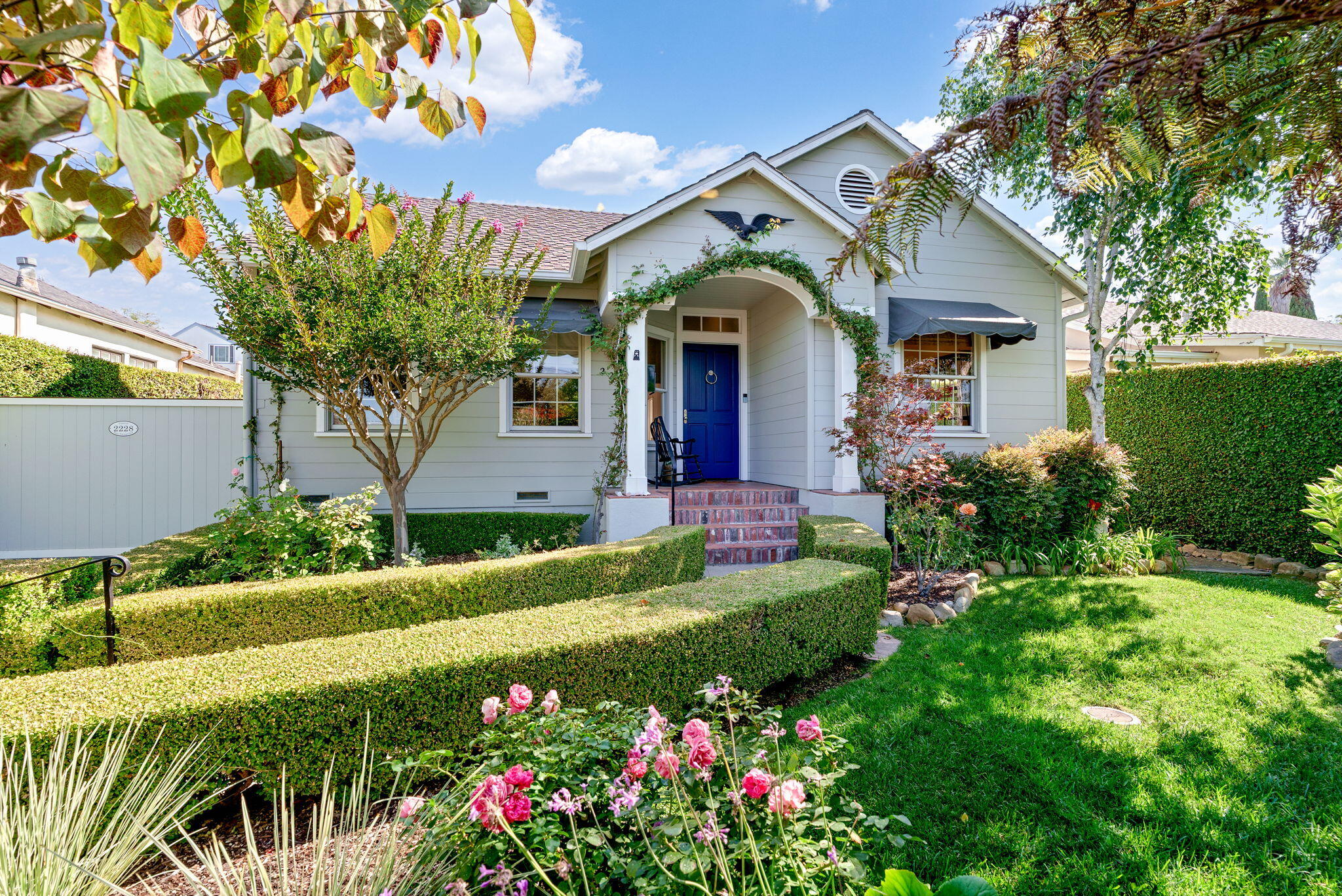 a front view of house and yard with beautiful flowers and green space