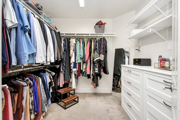 a view of walk in closet with clothes and shoes