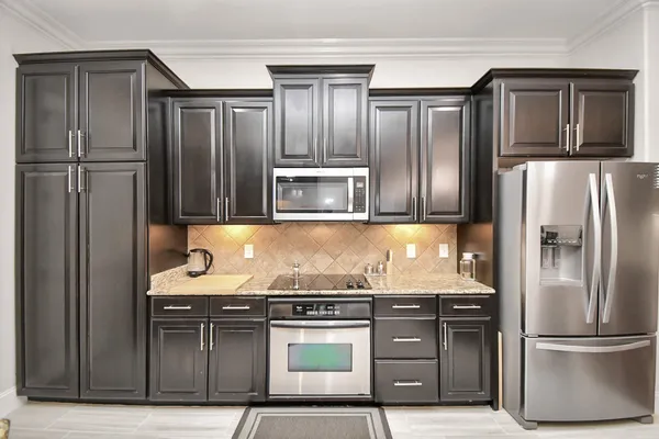 a kitchen with granite countertop stainless steel appliances wooden cabinets a stove and a refrigerator