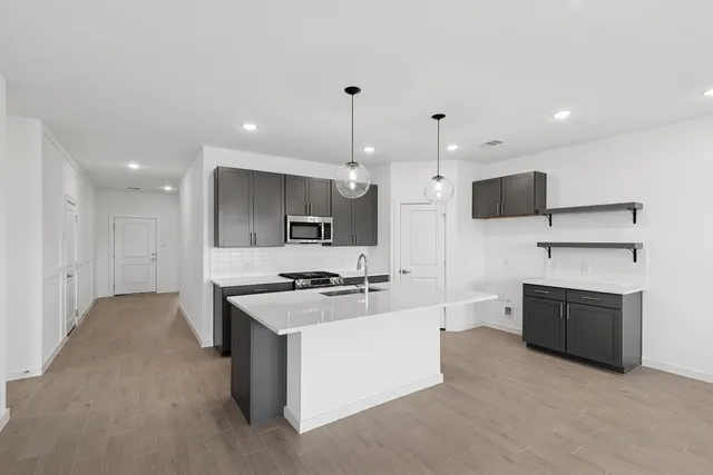 a large kitchen with stainless steel appliances a large counter top a stove a sink and a refrigerator