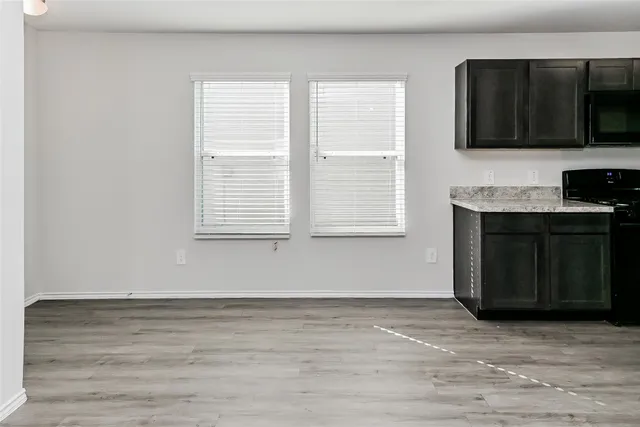 a view of empty room with kitchen and window