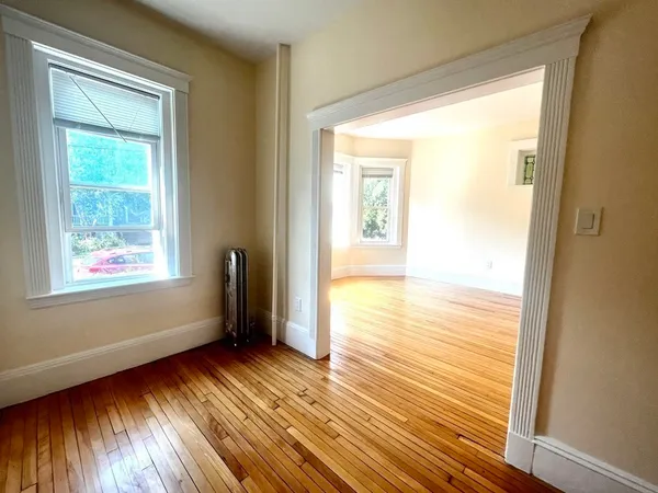 a view of an empty room with wooden floor and a window