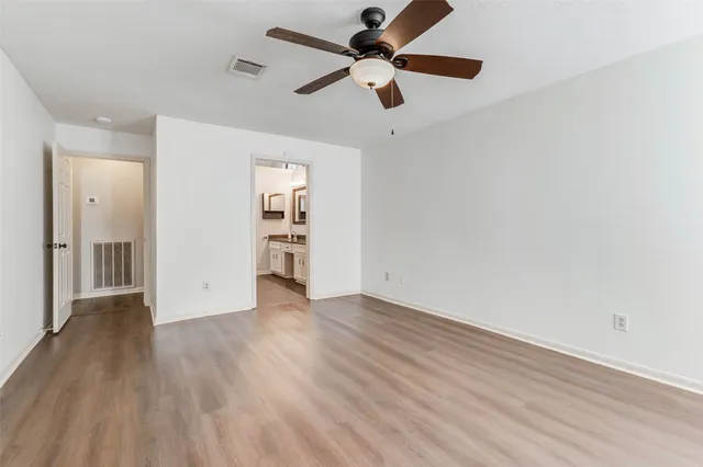 an empty room with wooden floor a ceiling fan and closet