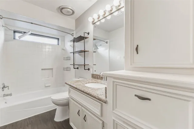 a bathroom with a granite countertop sink a toilet and shower