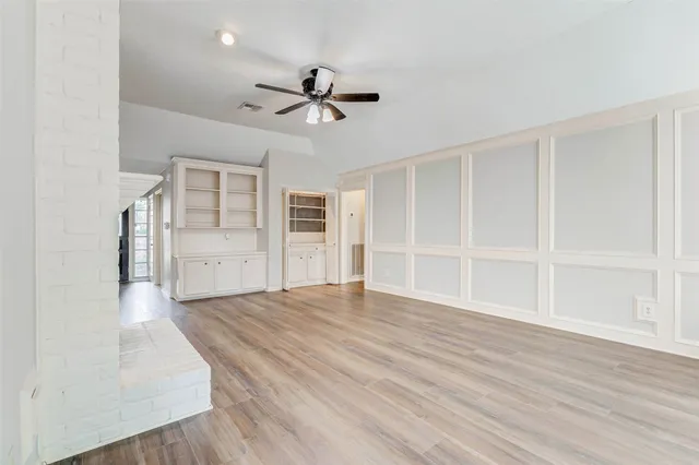 a view of empty room with wooden floor and ceiling fan
