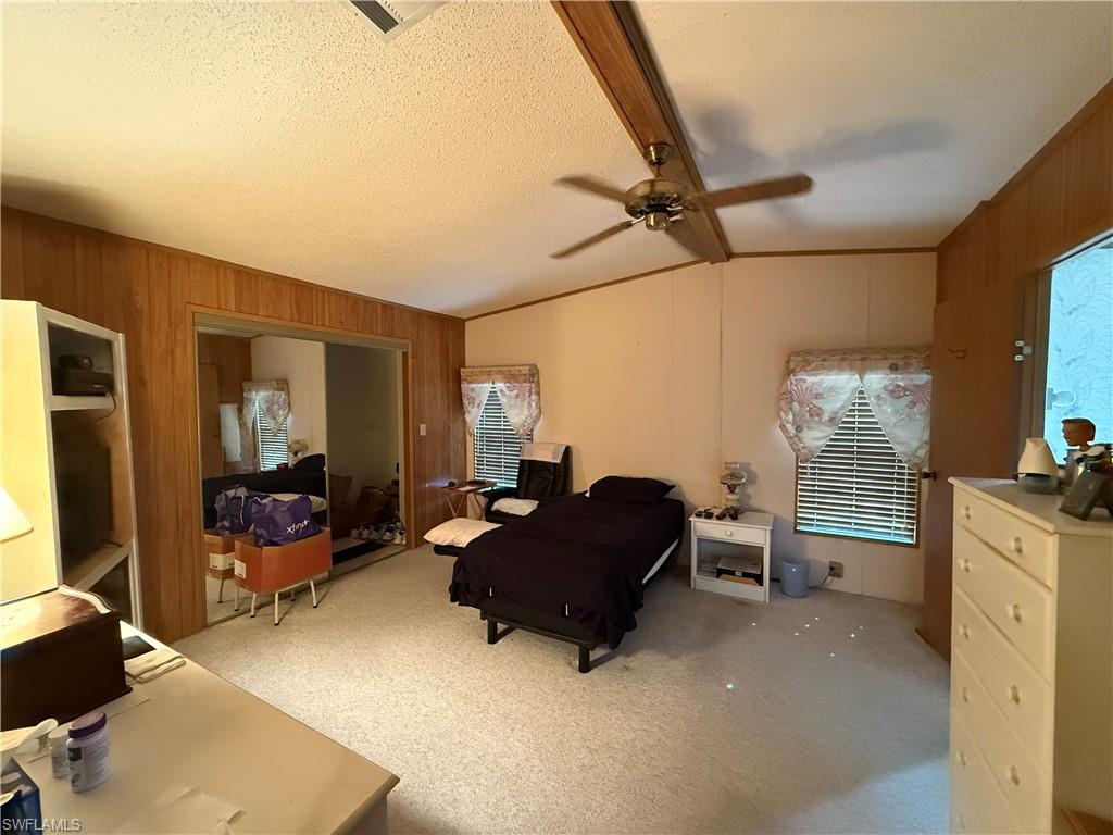 76 Atlantic Way, Unit 76 Naples, FL 34104 - Photo 14 of 18 Bedroom with vaulted ceiling, wooden walls, a textured ceiling, light carpet, and ceiling fan