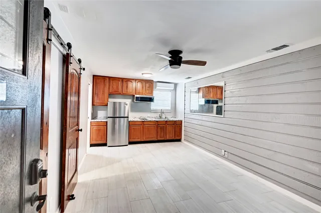 a large white kitchen with stainless steel appliances kitchen island granite countertop a refrigerator and a sink