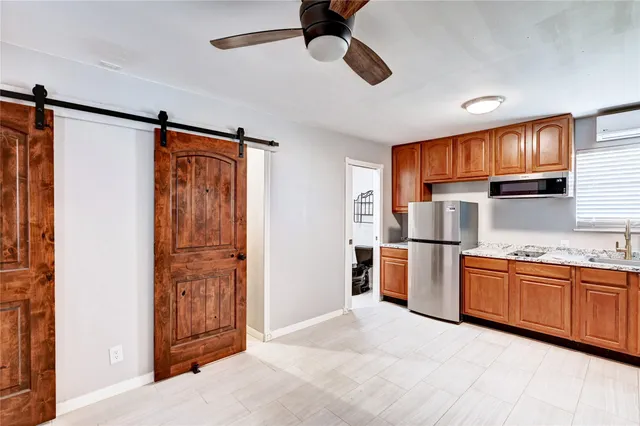 a kitchen with stainless steel appliances granite countertop a refrigerator a sink dishwasher a dining table and chairs with wooden floor