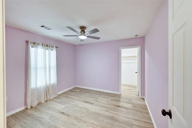 an empty room with wooden floor and ceiling fan