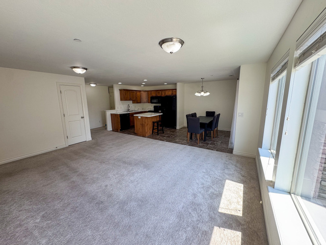909 South Main Street, Unit F Layton, UT 84041 - Photo 5 of 21 Spacious living area featuring light gray carpeting, multiple large windows, and overhead flush-mount lighting fixtures