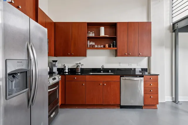 a kitchen with stainless steel appliances granite countertop a refrigerator a stove and a sink