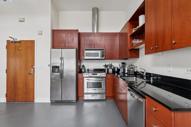 a kitchen with stainless steel appliances granite countertop a refrigerator a stove and a sink with wooden floor