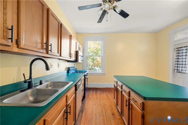 a kitchen with kitchen island a sink appliances cabinets and a large window