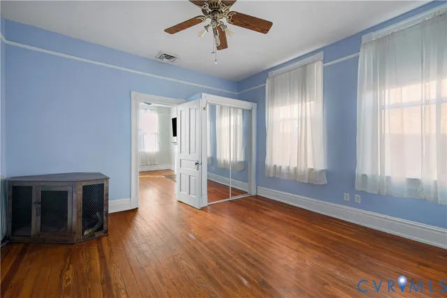 a view of empty room with wooden floor and fan