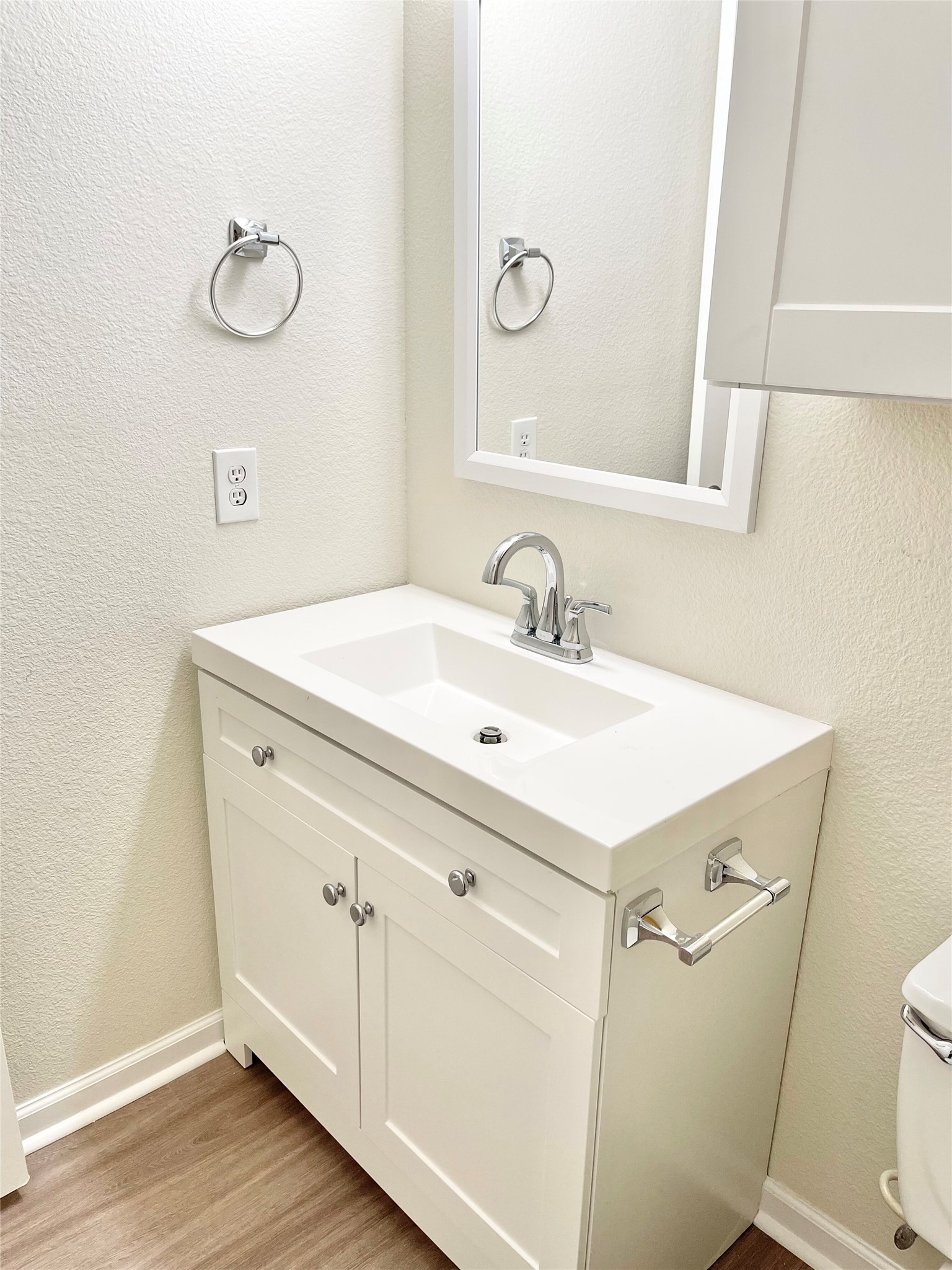 12513 Wethersby Way Austin, TX 78753 - Photo 13 of 16 Half bath with a textured wall, vanity, and light wood finished floors