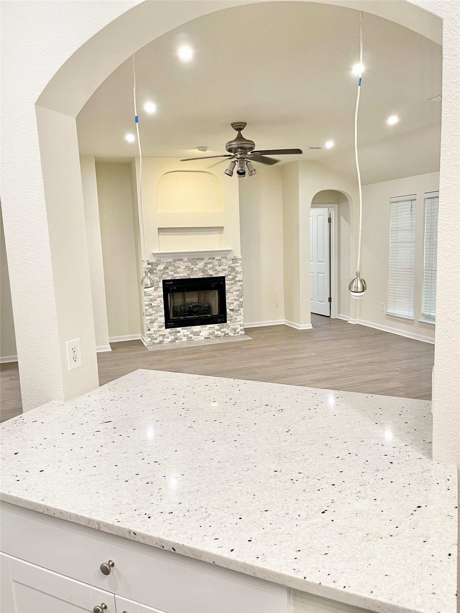 12513 Wethersby Way Austin, TX 78753 - Photo 16 of 16 Kitchen featuring arched walkways, light stone countertops, light wood-type flooring, open floor plan, and a fireplace with flush hearth