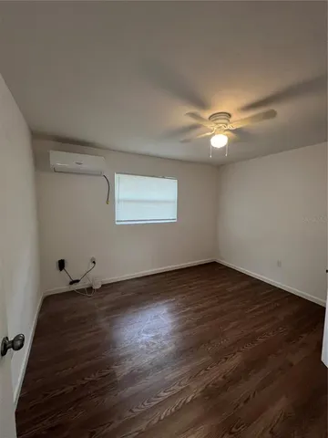 an empty room with wooden floor fan and window