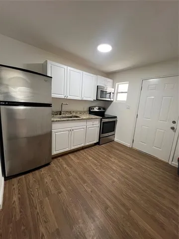 a kitchen with granite countertop a refrigerator sink and cabinets