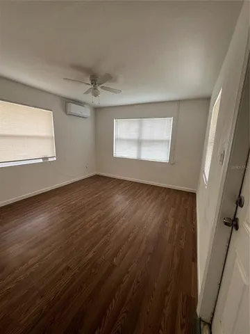 an empty room with wooden floor fan and windows