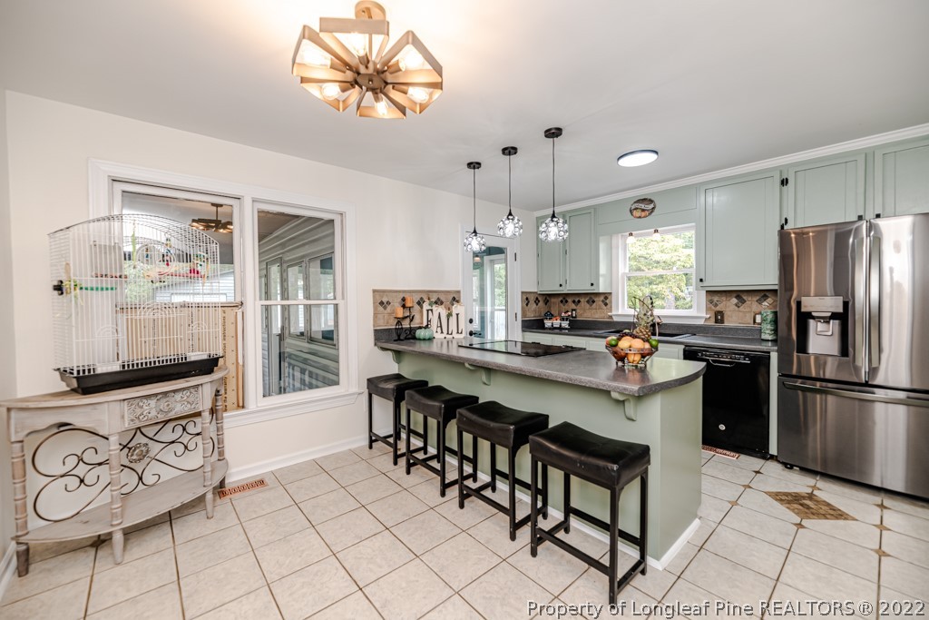 110 Cypress Road Cameron, NC 28326 - Photo 10 of 35 a kitchen with stainless steel appliances a refrigerator a stove a sink dishwasher and a dining table with wooden floor
