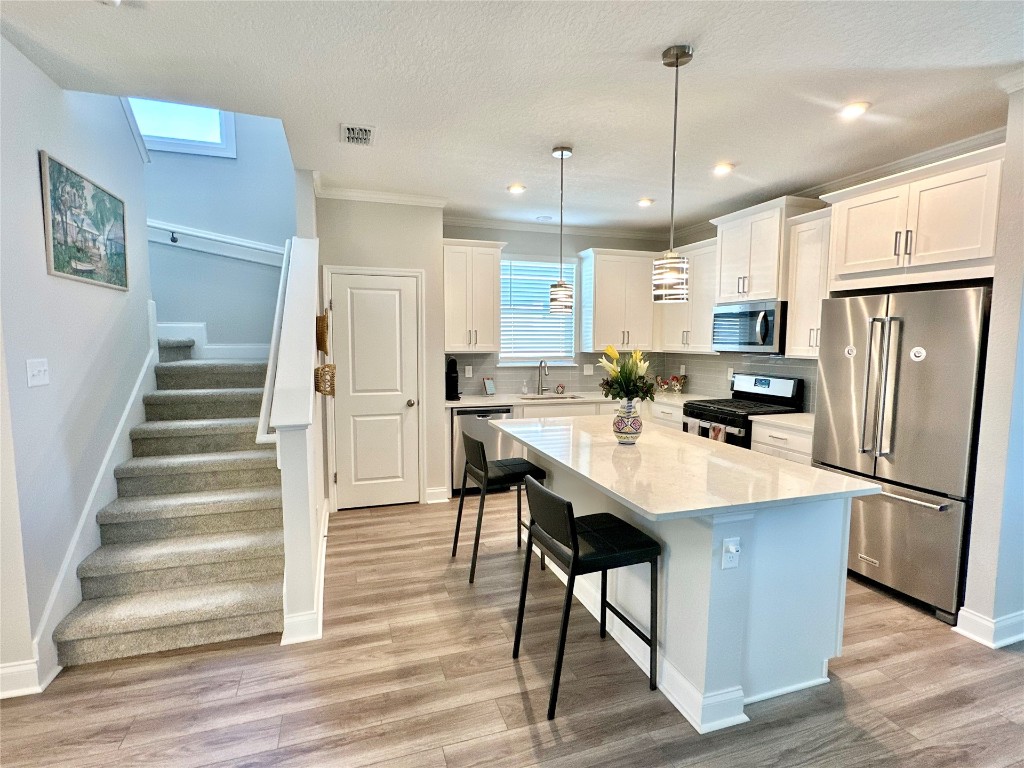 323 Sweetgum Street Yulee, FL 32097 - Photo 5 of 29 a kitchen with stainless steel appliances a refrigerator a stove a sink dishwasher a oven and a dining table with wooden floor
