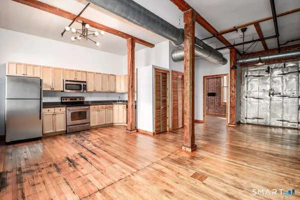 a kitchen with stainless steel appliances granite countertop a refrigerator a stove and a wooden floors