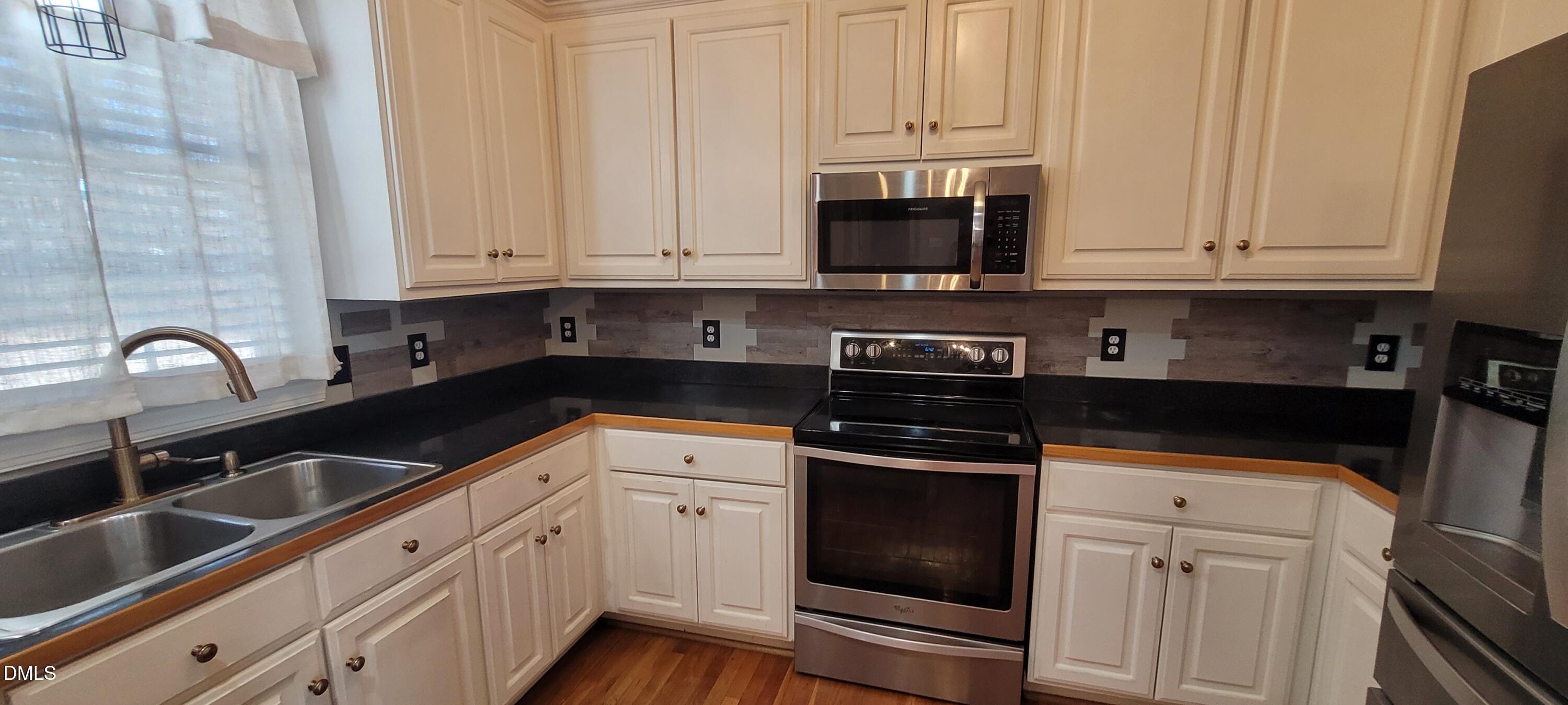226 Fletcher Ridge Road Timberlake, NC 27583 - Photo 8 of 30 a kitchen with white cabinets and stainless steel appliances