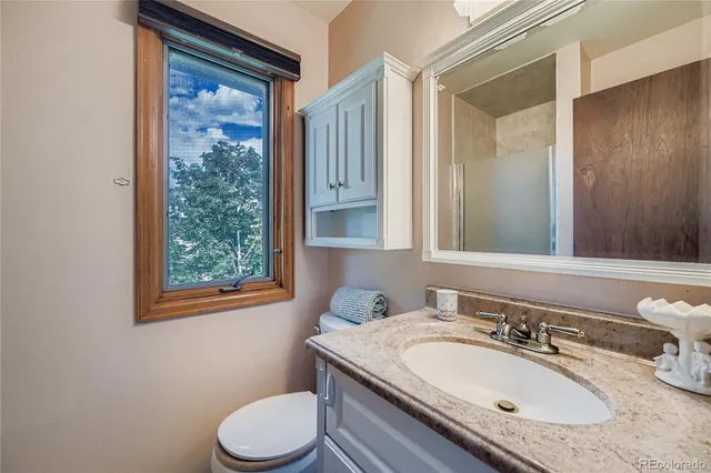 a bathroom with a granite countertop toilet sink and mirror