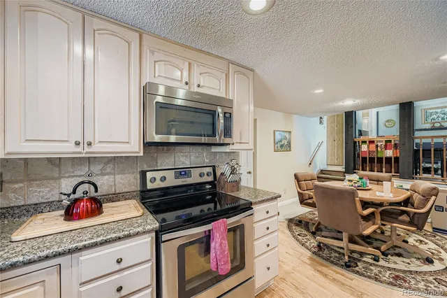 a kitchen with stainless steel appliances granite countertop a stove top oven a sink dishwasher and cabinets with wooden floor