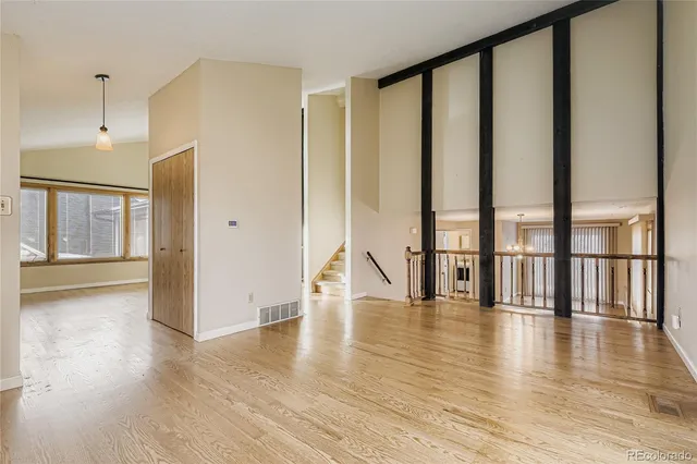 a view of an empty room with wooden floor and windows