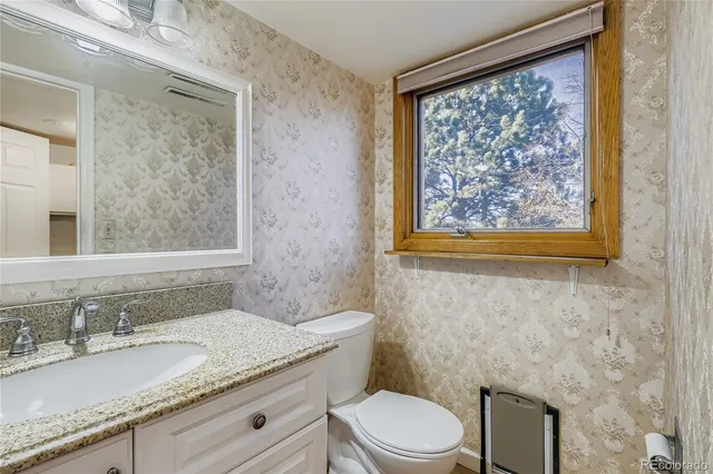 a bathroom with a granite countertop toilet a sink and a mirror