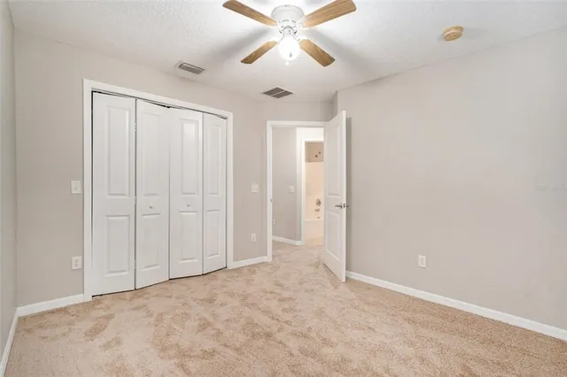 a view of an empty room and chandelier fan