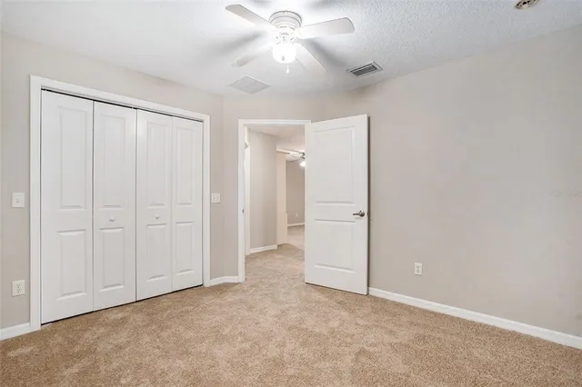 an empty room with closet and a ceiling fan