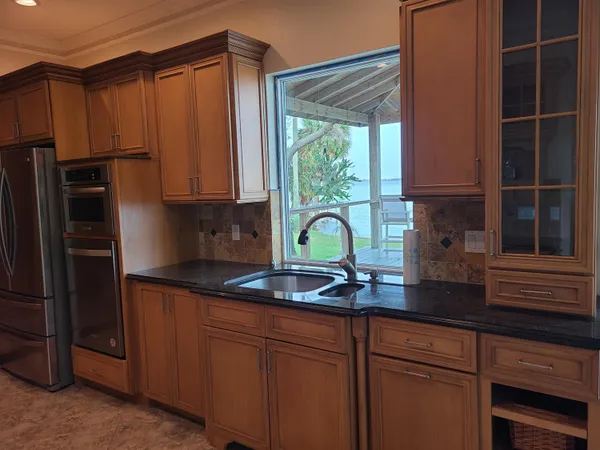 a kitchen with stainless steel appliances granite countertop a sink a refrigerator and a granite counter tops