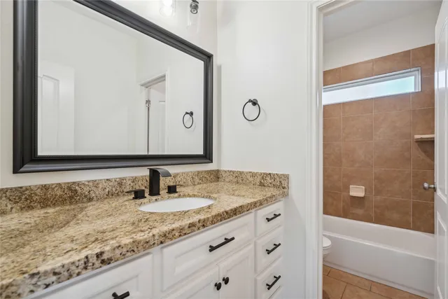 a bathroom with a granite countertop sink and a mirror a bathtub
