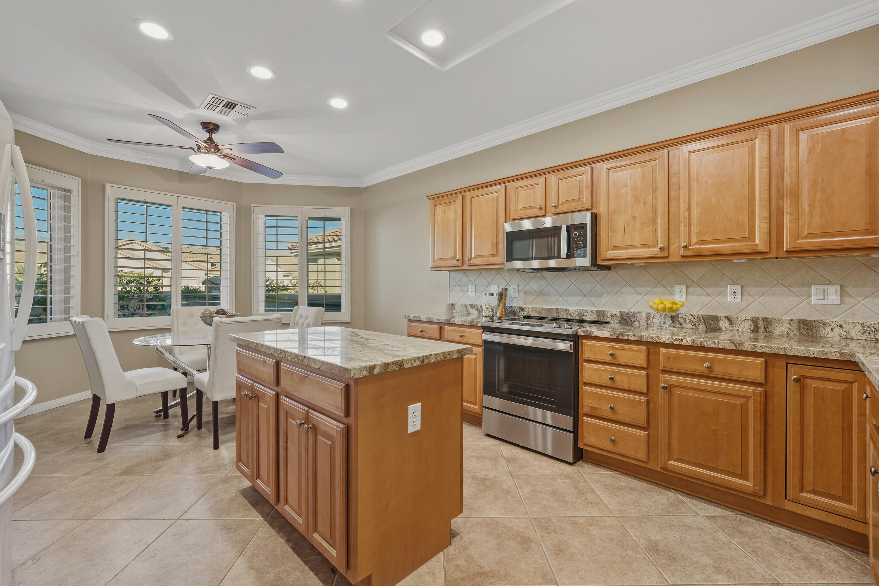 78589 Rainswept Way Palm Desert, CA 92211 - Photo 14 of 30 a kitchen with granite countertop wooden cabinets a sink a stove a dining table and chairs