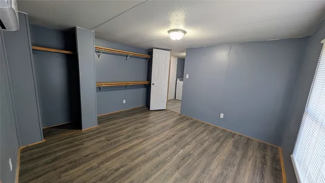 a view of an empty room with wooden floor and closet