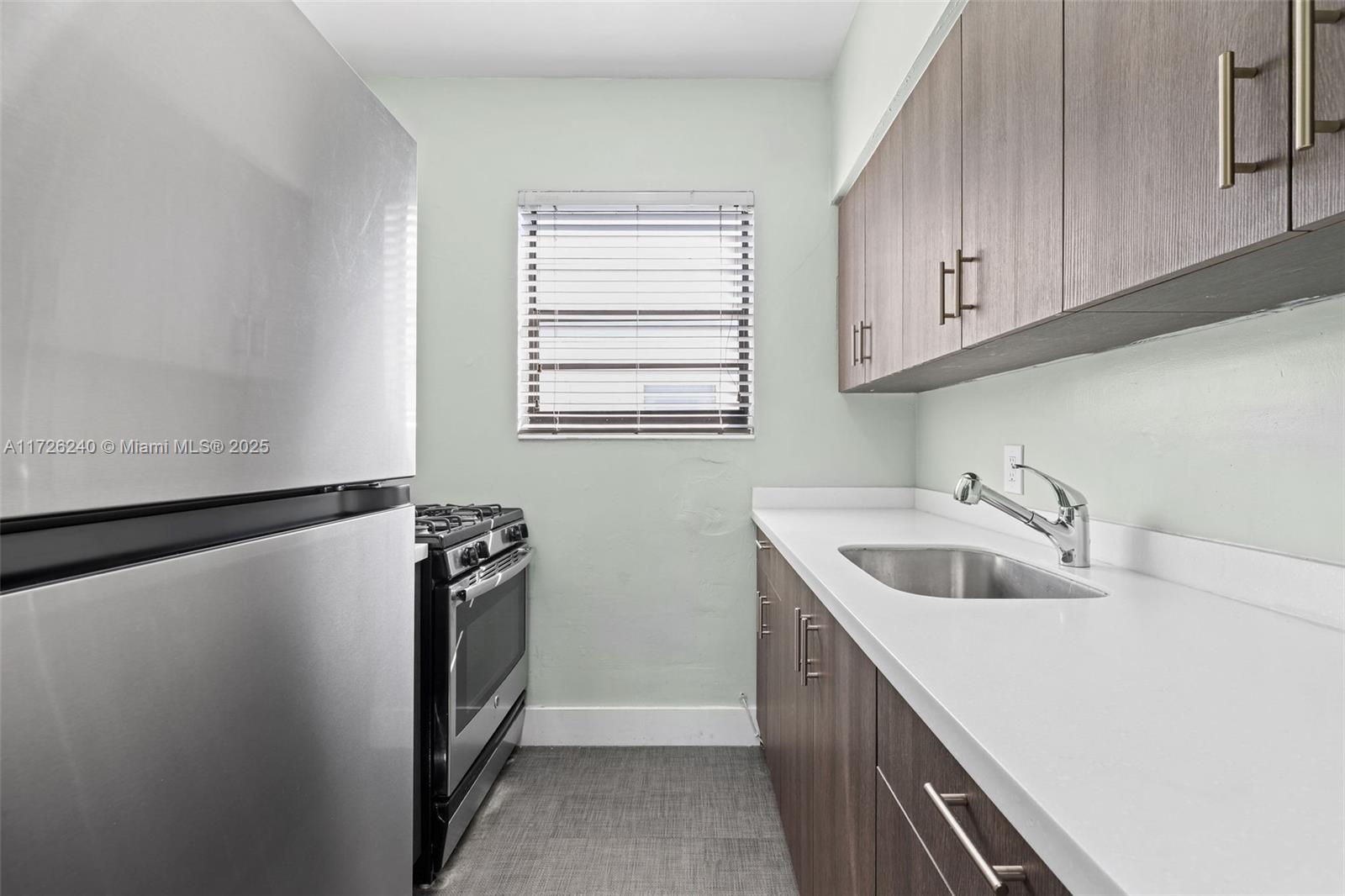 7745 Harding Avenue, Unit 22 Miami Beach, FL 33141 - Photo 6 of 9 a kitchen with a sink a refrigerator and cabinets