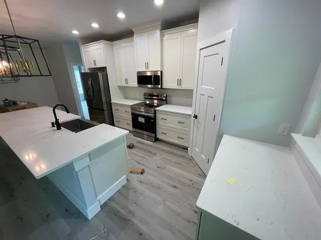 a kitchen with a sink a stove a refrigerator a washer dryer and white cabinets