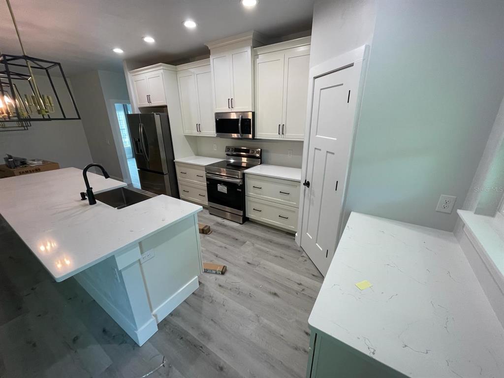 4102 Northwest 26th Drive Gainesville, FL 32605 - Photo 3 of 11 a kitchen with a sink a stove a refrigerator a washer dryer and white cabinets