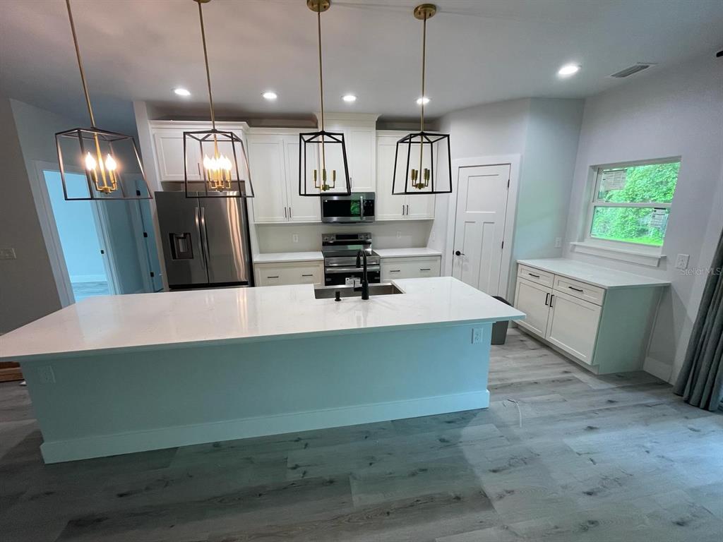 4102 Northwest 26th Drive Gainesville, FL 32605 - Photo 5 of 11 a kitchen with stainless steel appliances granite countertop a sink a stove and a refrigerator
